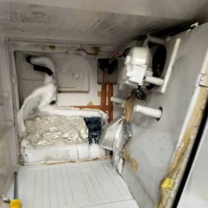 Chest freezer with heavy ice buildup being serviced