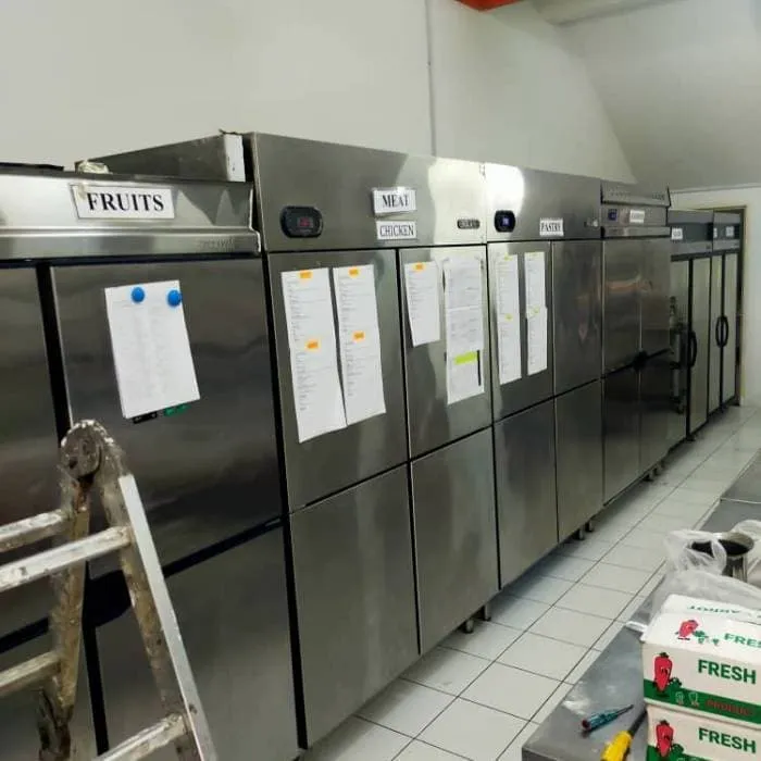 Technician servicing stainless steel upright freezer
